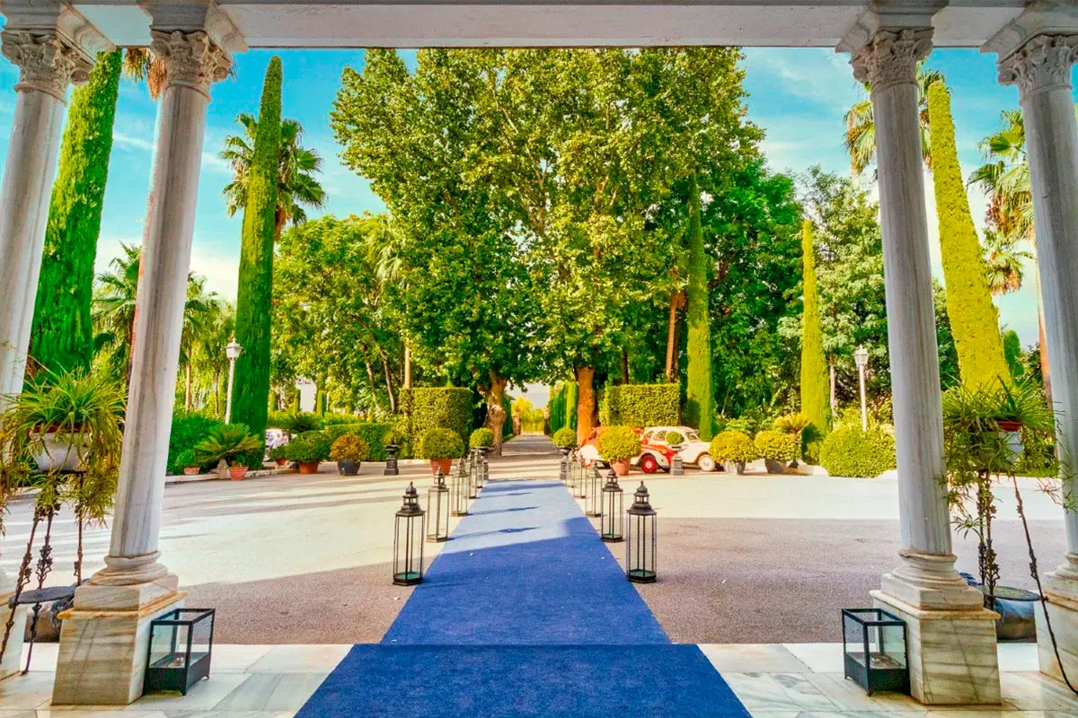 Vista desde la entrada del palacete de Huerta del sello, con alfombra extendida y arboles, cipreses y jardines