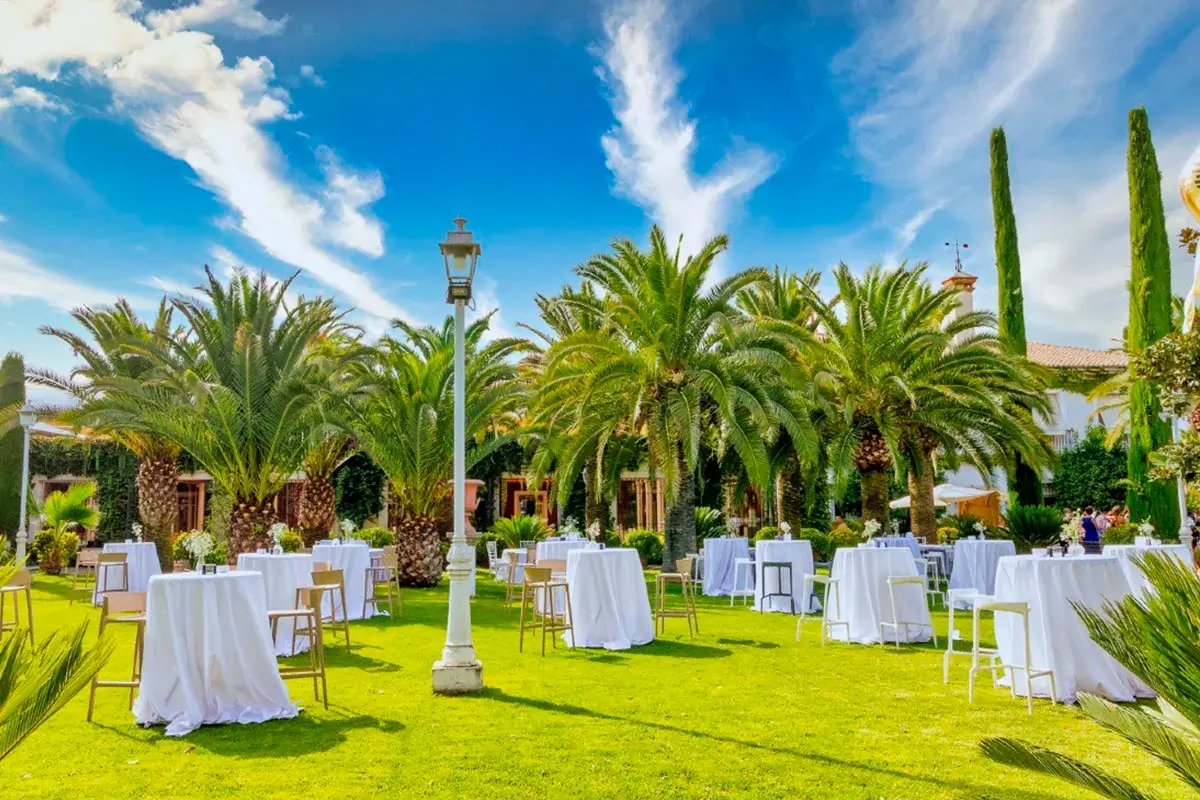 Mesas y sillas para cóctel de empresa en jardines con palmeras en Huerta del sello