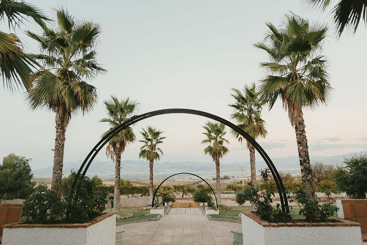 Paseo con arcos y palmeras con jardín en cada lateral