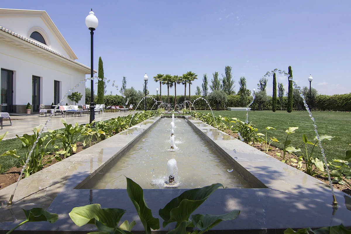 Fuente en la finca de Viñas de Belén con vista a jardines a la derecha y el edificio a la izquierda.