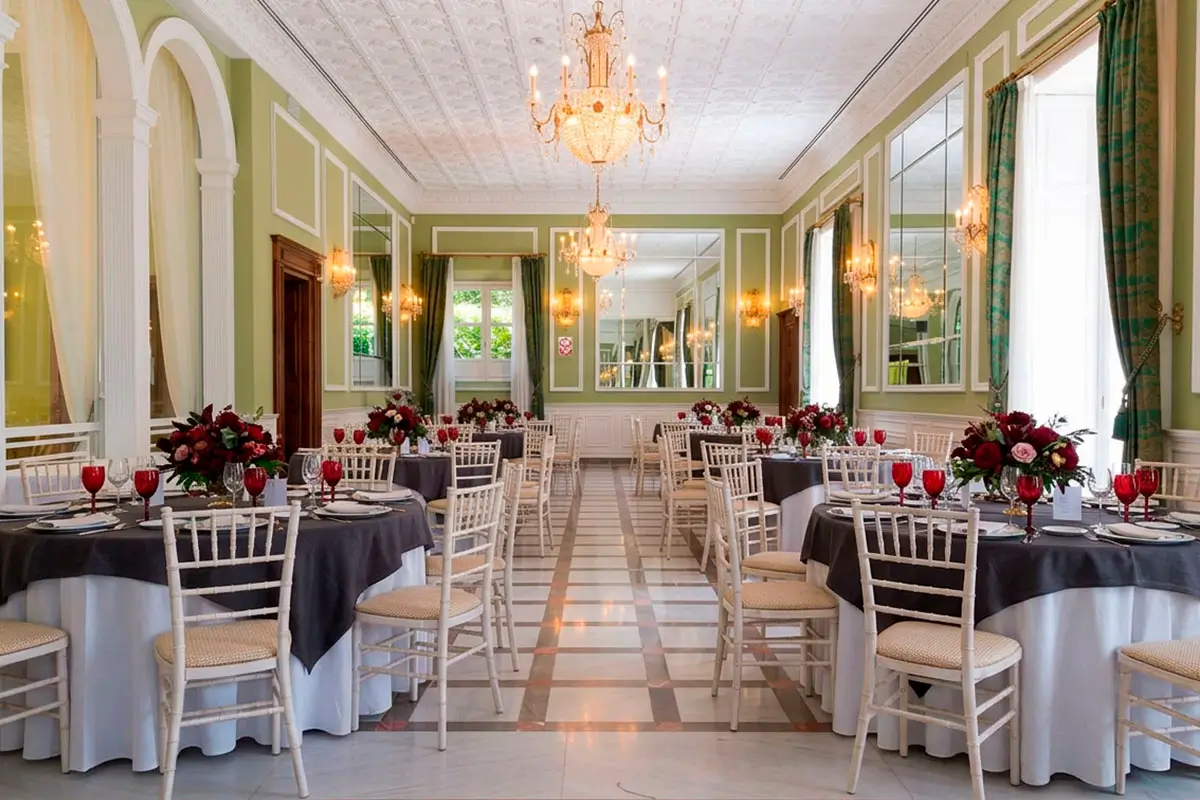 Montaje de mesas y sillas con decoración elegante para celebración de evento en el salón interior del Carmen de los Mártires