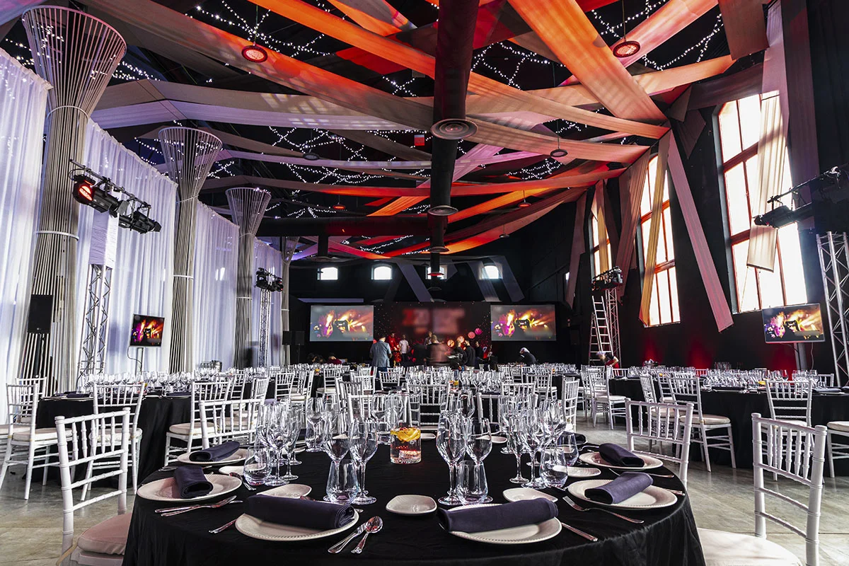 Montaje de mesas de banquete totalmente equipadas junto a sillas de palilleria blancas para celebrar un banquete en La Azucarera